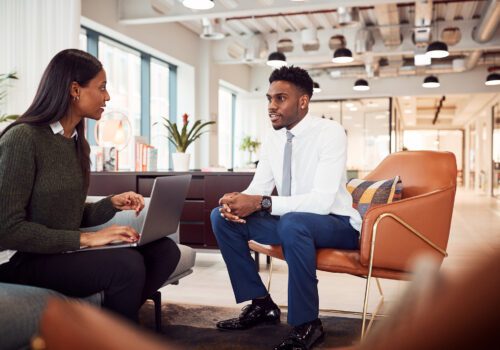 Businesswoman Interviewing Male Job Candidate In Seating Area Of Modern Office